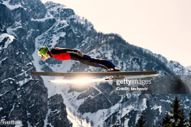 side view of young male ski jumper in mid-air, sun reflection - ski jumping stock pictures, royalty-free photos & images