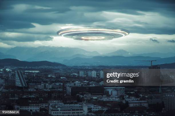 onheilspellende ufo boven de stad - alien stockfoto's en -beelden