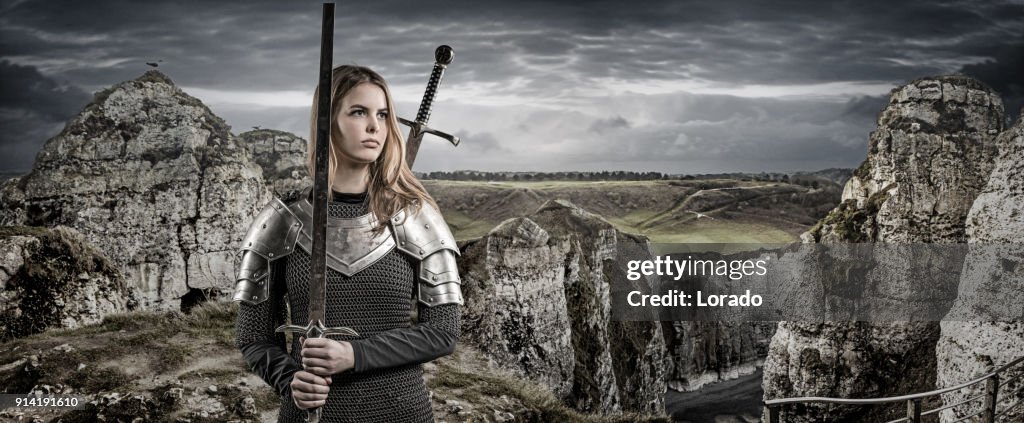 Espada empunhando viking guerreiro loira fêmea jovem na zona rural das montanhas selvagens