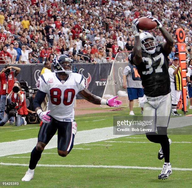 Cornerback Chris Johnson of the Oakland Raiders intercepts a pass intended for wide receiver Andre Johnson of the Houston Texans in the first half at...