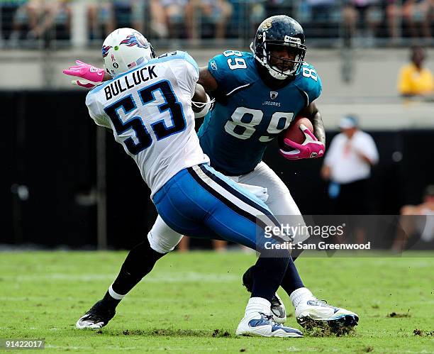 Marcedes Lewis of the Jacksonville Jaguars is tackled by Keith Bullock of the Tennessee Titans during the game at Jacksonville Municipal Stadium on...