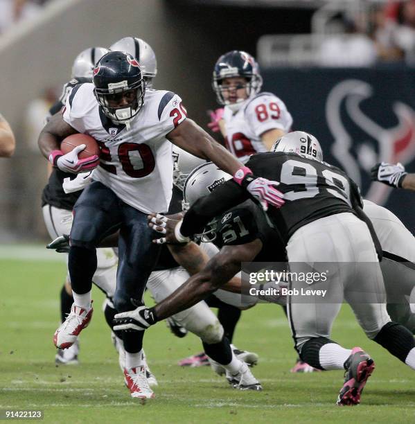 Running back Steve Slaton of the Houston Texans pushes aside defensive end Greg Ellis and defensive tackle Gerard Warren of the Oakland Raiders...