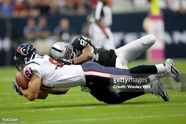Owen Daniels of the Houston Texans catches a pass with Michael Huff of the Oakland Raiders on his back at Reliant Stadium on October 4, 2009 in...