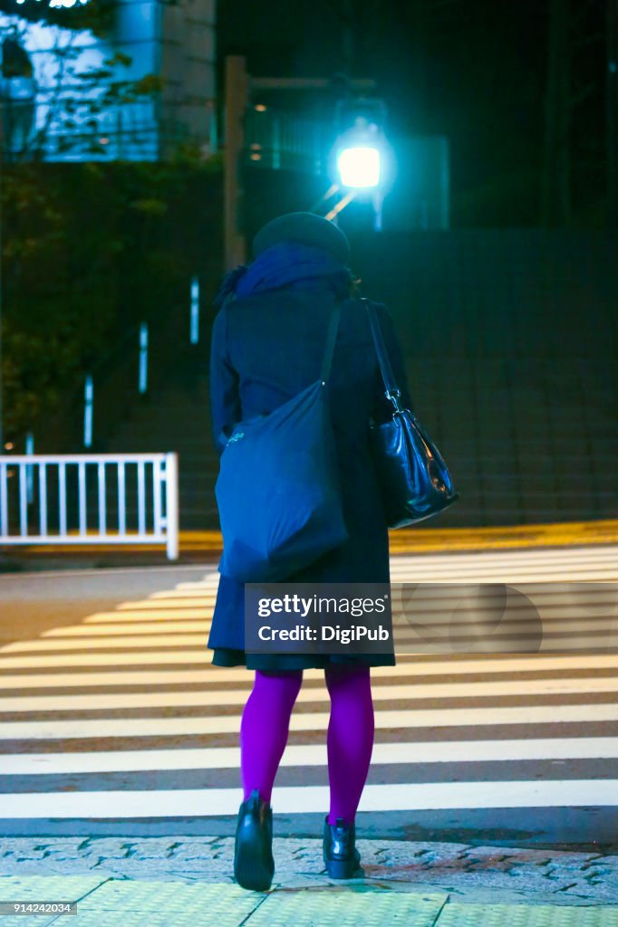 Young woman crossing road in a cold midnight