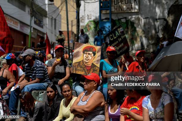 Supporter of Venezuelan President Nicolas Maduro holds a portrait of late Venezuelan President Hugo Chavez during a rally to commemorate the 26th...