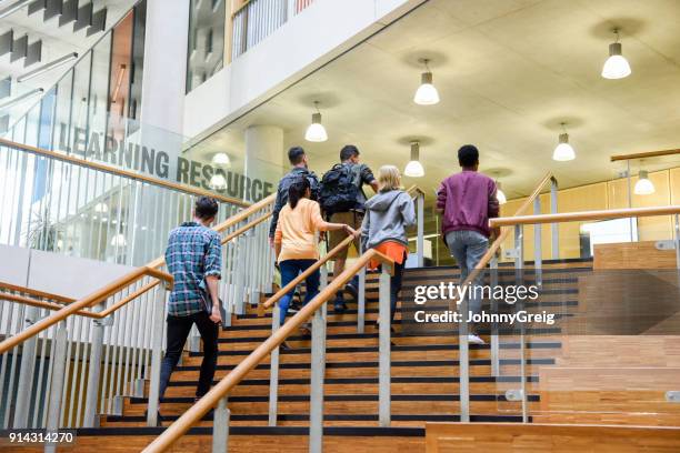 six students walking up wooden steps in modern college building - post secondary education stock pictures, royalty-free photos & images