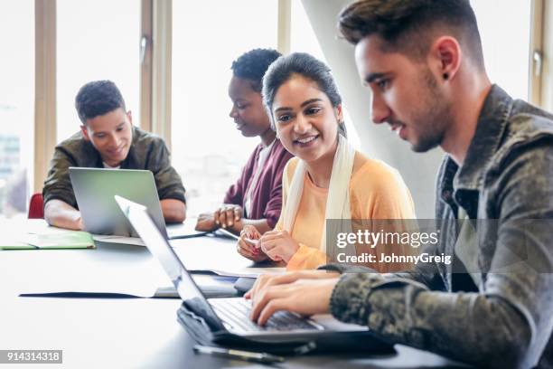 若い男が女子学生を見ていると、笑顔でラップトップを使用して - イングランド ストックフォトと画像