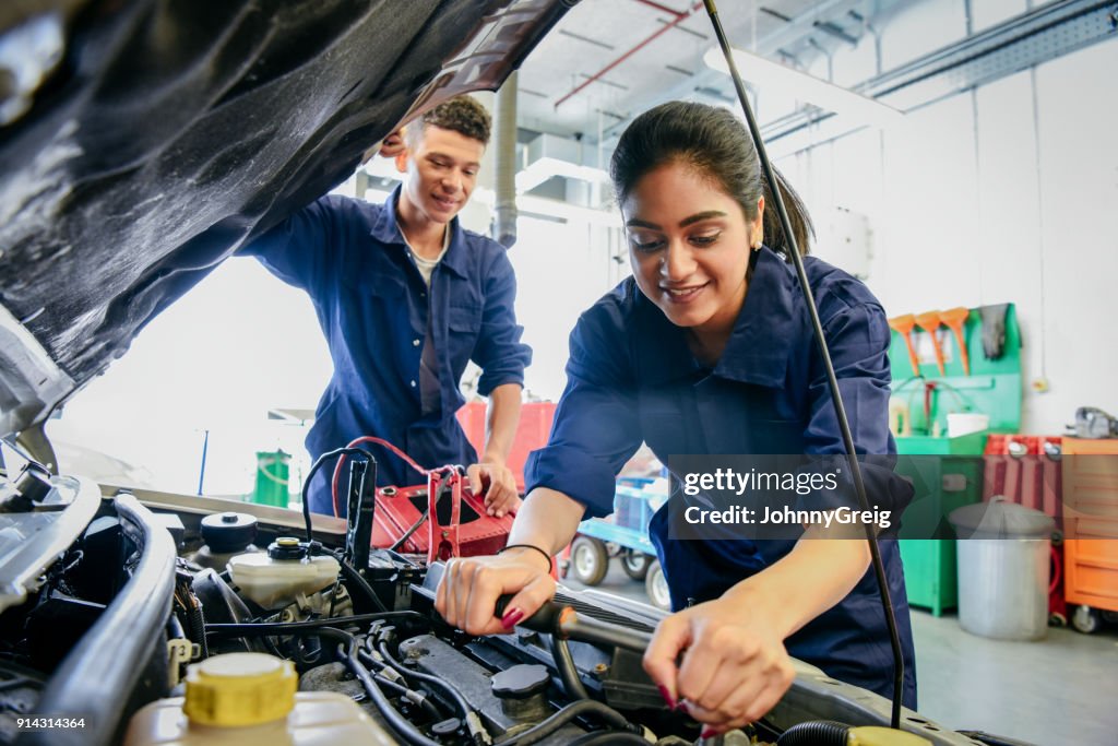 Weibliche Mechaniker Festsetzung Auto, junger Mann beobachten