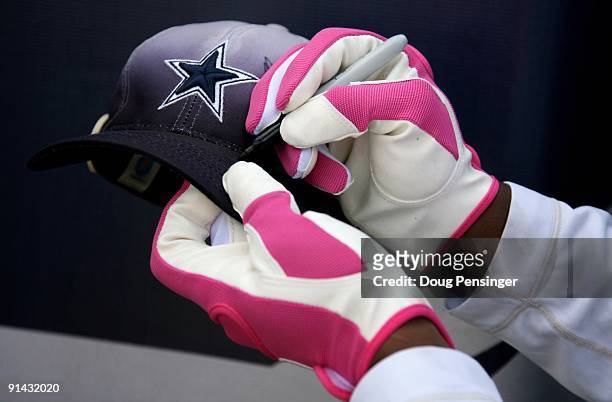Sam Hurd of the Dallas Cowboys wears pink gloves as he signs an autograph for a fan as the Cowboys face the Denver Broncos during NFL action at...