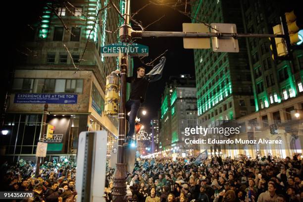 Man climbs a traffic pole as Philadelphia Eagles fans celebrate victory in Super Bowl LII against the New England Patriots on February 4, 2018 in...
