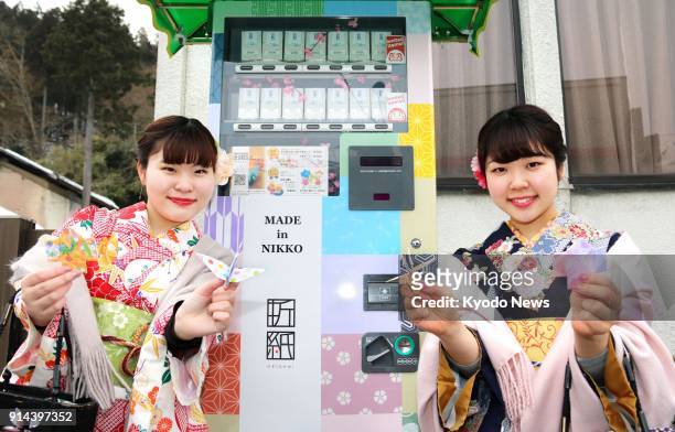 Tourists hold origami on Feb. 1 bought from a vending machine set up near the UNESCO World Heritage site Nikko Toshogu Shrine in Tochigi Prefecture,...