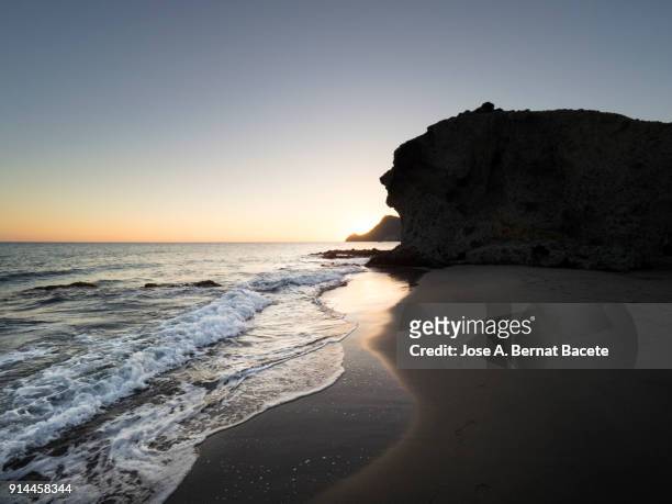 sunset  with nightfall light and the moon in the sky, on the beach and rocky coast of the cabo de gata with formations of volcanic rock. cabo de gata - nijar natural park, monsul creek, biosphere reserve, almeria,  andalusia, spain - biosphere planet earth stock pictures, royalty-free photos & images