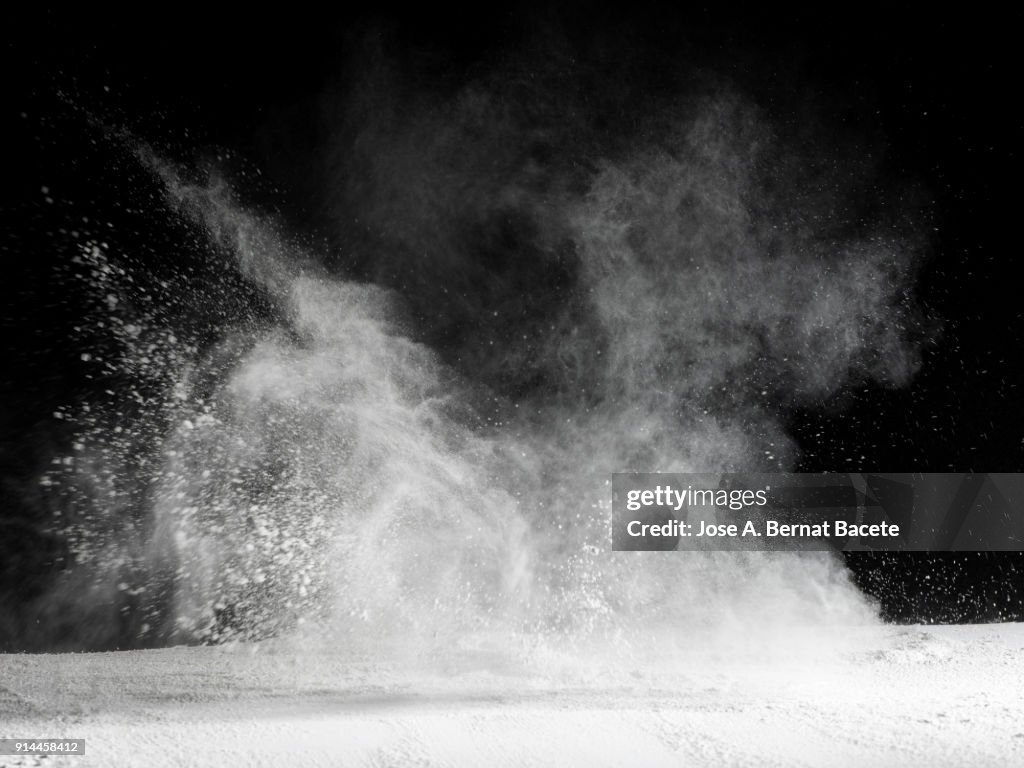 Explosion by an impact of a cloud of particles of powder  of color white and a black background