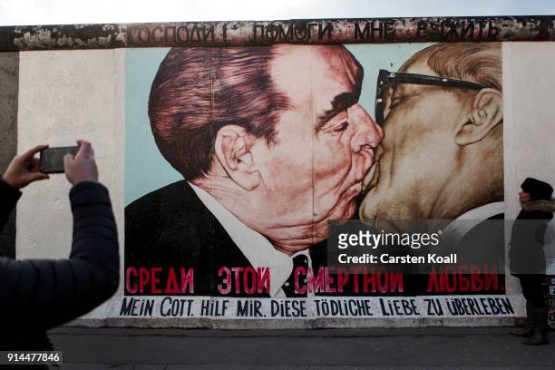 Visitors stand in front of a mural depicting former Soviet leader Leonid Brezhnev kissing former communist East German leader Erich Honecker at the...