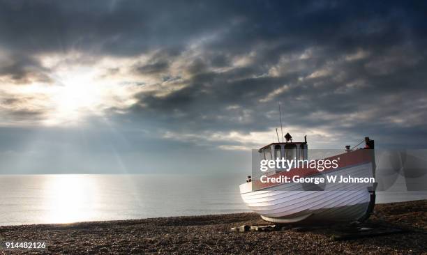 fishing boat on a shingle beach at dungeness. - dungeness stock pictures, royalty-free photos & images