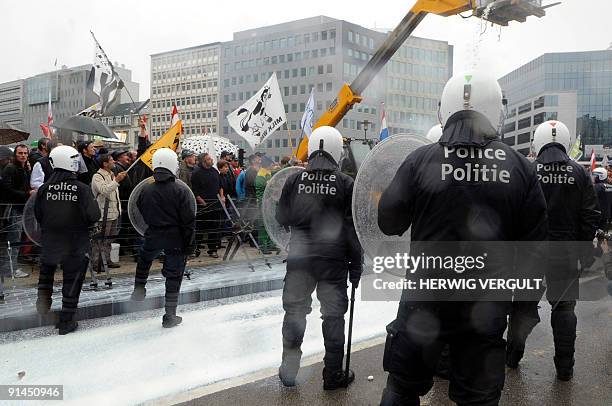 Policemen stand by milk farmers coming from various European countries protesting against falling milk prices outside the European Headquarters in...