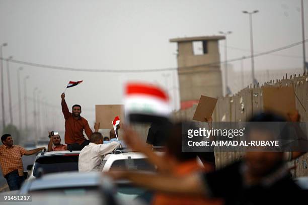 Former Iraqi prisoners ride in cars as they celebrate waving the national flag on September 28 in Baghdad following their release from jail. Thirty...