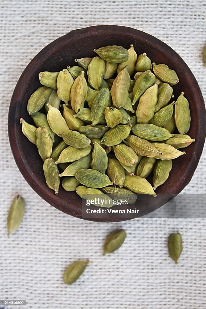Cardamom/spice in a clay bowl against white background