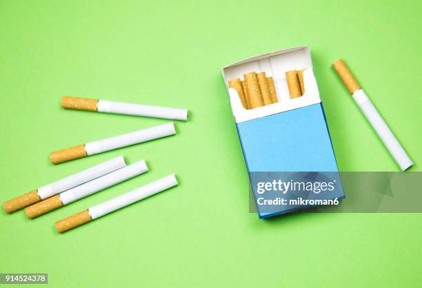 cigarette box and cigarettes on green background - paquete de cigarrillos fotografías e imágenes de stock