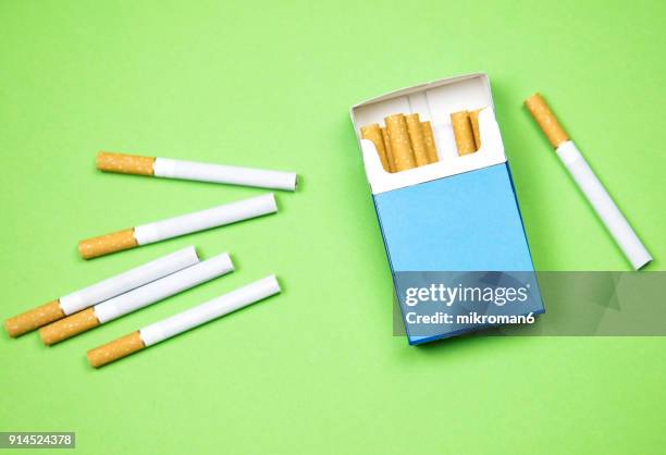 cigarette box and cigarettes on green background - cigarette pack stockfoto's en -beelden