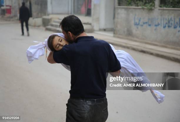 Graphic content / TOPSHOT - A Syrian father kisses the body of his daughter, 6-year-old Aya, ahead of her funeral in Zamalka, near Syria's capital...