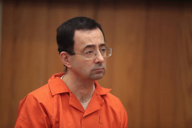 Larry Nassar stands as he is sentenced by Judge Janice Cunningham for three counts of criminal sexual assault in Eaton County Circuit Court on...
