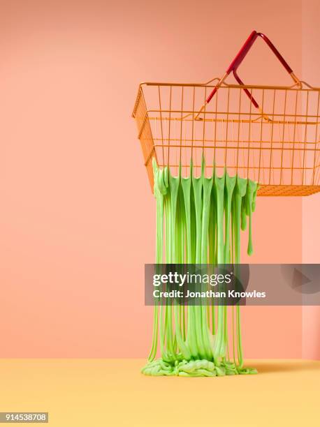 slime fripping through the holes in a wire shoping basket - slime stockfoto's en -beelden