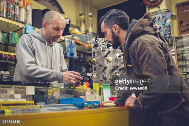 man shopping fishing equipment in a store - barbed hook stock pictures, royalty-free photos & images