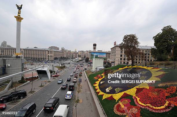 Cars pass by a huge clock made of flowers on Independence Square in Kiev on September 24, 2009. AFP PHOTO/ SERGEI SUPINSKY