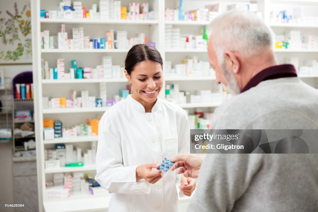 Female pharmacist giving medications to senior customer