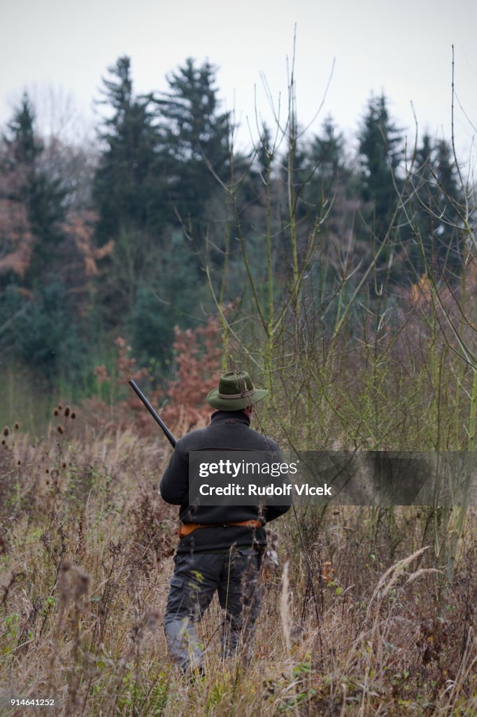 Hunter wearing a hat with a rifle in a forest