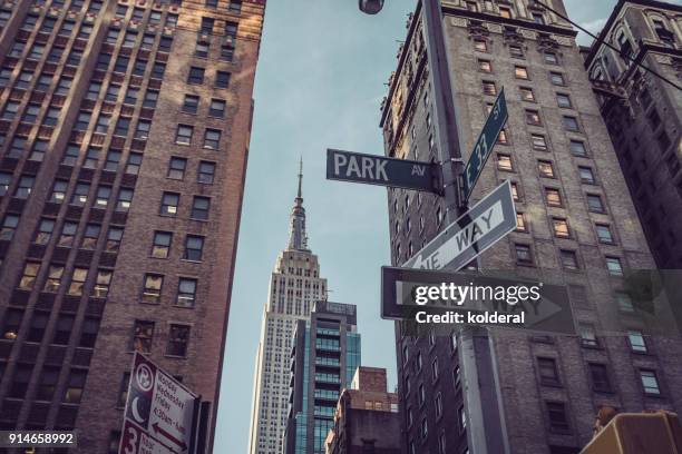 distant view of empire state building from park avenue. manhattan, new york - midtown stock-fotos und bilder