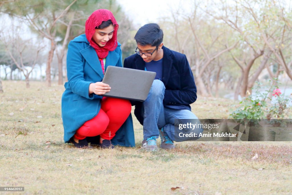 A Boy And A Girl Working On Laptop In The Garden