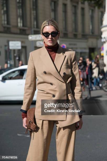 Fashion blogger Camille Charriere wears an Acne polo neck sweater, Victoria Beckham suit, Nanushka bag and Le Specs sunglasses day 5 of Paris Womens...