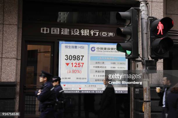 Pedestrians walk past an electronic screen displaying the Hang Seng Index figure in Hong Kong, China, on Tuesday, Feb. 6, 2018. The Hang Seng Index's...