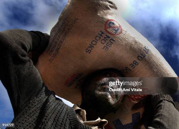 Malawian suffering from a severe food shortage carries corn home from a food distribution center July 4, 2002 near Blantyre, Malawi. In Malawi, and...