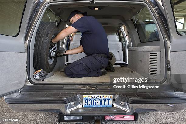 Looking for hidden weapons and ammunitions, an ICE agent inspects a southbound vehicule on the Lincoln-Juarez Bridge separating the U.S. From Mexico,...