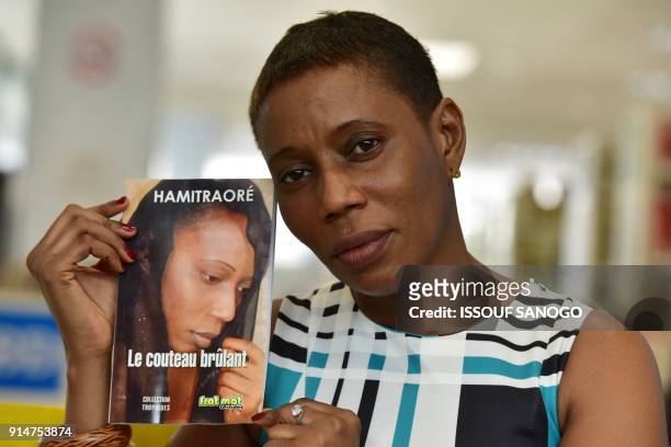 Ivorian writer Hami Traore poses with her book "Le couteau brulant", in which she tells the story of her genital mutilation in the region of Bouake...