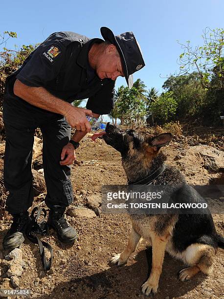 Shane 'Fish' Salmond from the New Zealand Police Specialist Search Group gives his sniffer dog 'Jess' a drink of water during the search for victims...