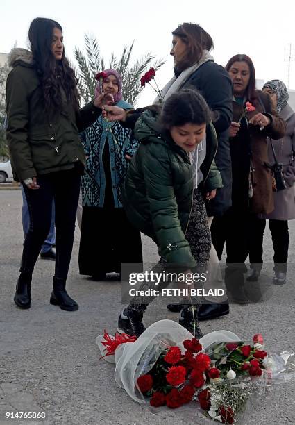 Basma Khalfaoui , the widow of murdered Tunisian opposition figure Chokri Belaid, hands a flower to his elder daughter Nayrouz while his younger...