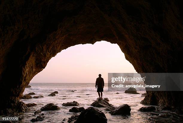 silhouette man standing in sea cave at sunset - light at the end of the tunnel stock pictures, royalty-free photos & images