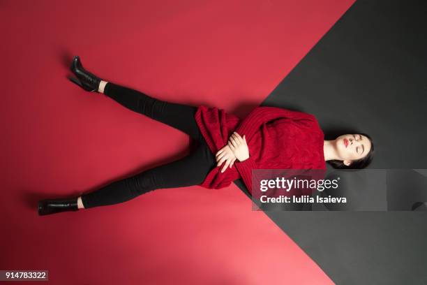 model in red lying on studio floor - sleeping posture stock pictures, royalty-free photos & images