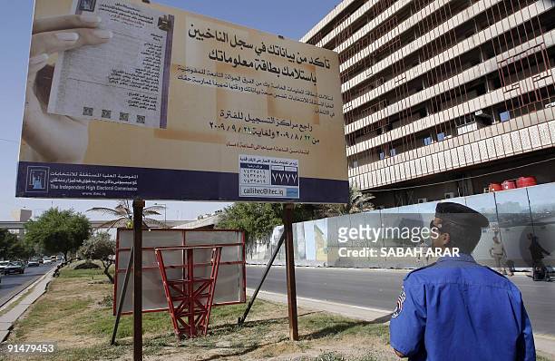 An Iraqi policeman reads an electocal committe information billboard urging people to update their voting record in Baghdad on October 6, 2009....