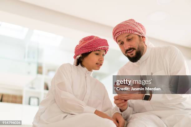 father talking with his son using smart phone - saudi home stock pictures, royalty-free photos & images