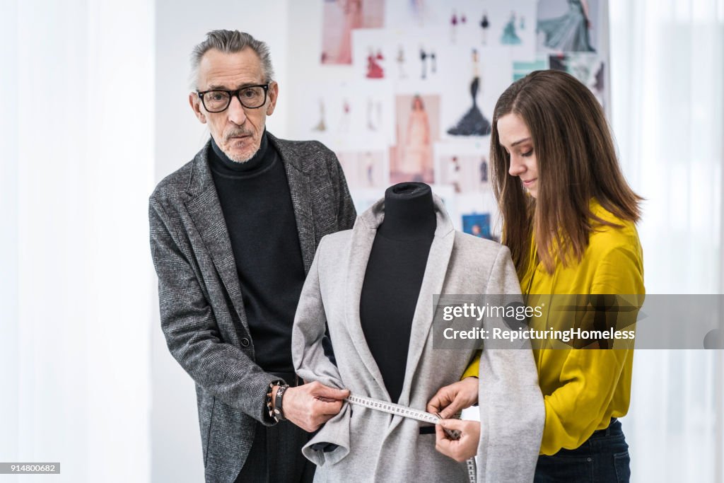 Zwei Mode-Designer vermessen Stoff an einer Ankleidepuppe