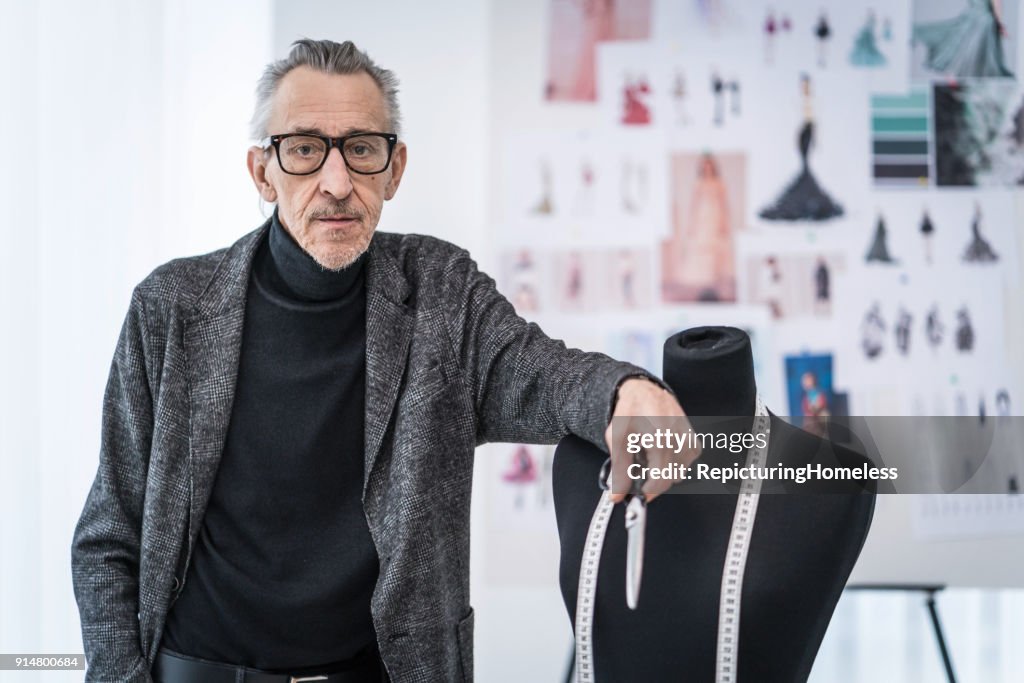 A fashion designer leaning against a mannequin