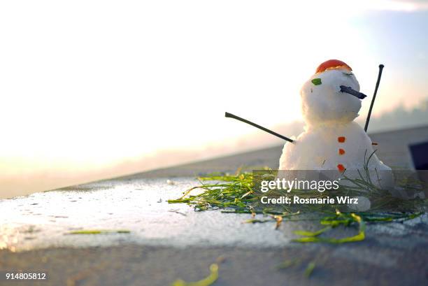 snowman sitting on wall in the sun, melting - melted snowman stock-fotos und bilder