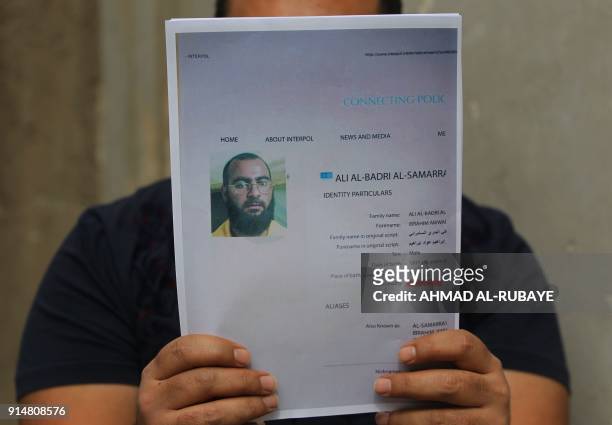 An Iraqi man holds printed profiles of Abu Bakr al-Baghdadi released by Iraqi authorities on February 6, 2018. Iraqi authorities issued a new list of...