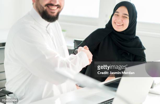 arabic business male and female closing the deal with handshaking - business hand shake with arabs stock pictures, royalty-free photos & images