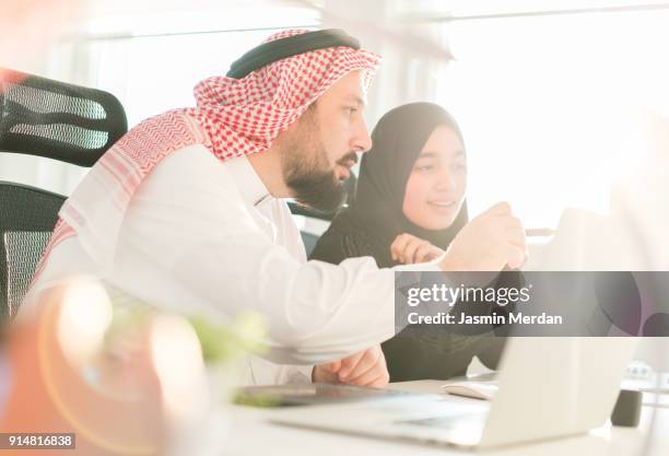 arabic business male and female working together on project - saudi youth stock-fotos und bilder